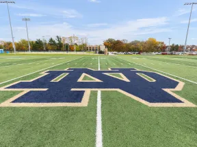 Notre Dame logo prominently displayed on a football field under a clear blue sky.