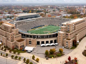 Aerial view of a large stadium surrounded by buildings and trees in autumn colors.