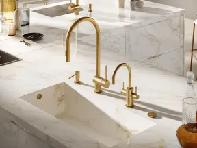 Modern kitchen sink with built-in marble basin and gold-tone faucets on a marble countertop.
