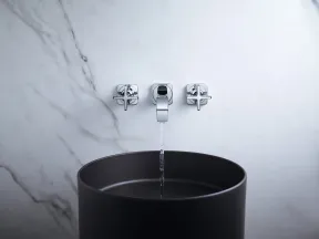 Modern bathroom faucet with water flowing into a sleek black basin against marble wall.