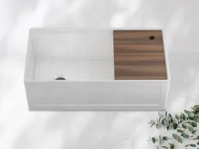 White kitchen sink with integrated wooden cutting board on a light marble surface with eucalyptus branch.