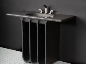 Modern black stone sink with sleek faucet mounted on a sculptural base against a dark wall.