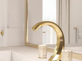 Elegant gold curved faucet with decorative textured handles on a beige bathroom countertop with mirror.