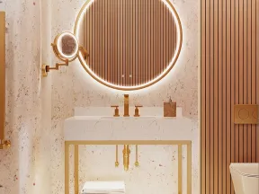 Modern bathroom with illuminated round mirror, gold fixtures, white marble sink, and stacked towels under vanity.