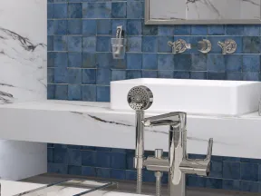 Modern bathroom with blue tiled wall, white marble surfaces, chrome faucet, and rectangular sink under mirror.
