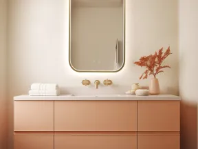 Modern bathroom vanity with illuminated mirror, beige countertop, peach cabinets, and decorative vase with dried flowers.