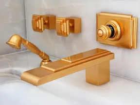 Modern gold matte bathroom faucet set with wall-mounted handles and handheld showerhead on marble tiles.
