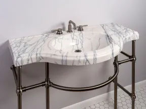 White marble bathroom sink with grey veining and brushed metal fixtures on bronze frame stand.