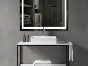 Modern bathroom vanity with illuminated square mirror, white sink, folded towels, and gray concrete walls.