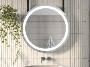 Modern bathroom with a round LED mirror, beige countertop sink, vertical tiled wall, and hanging plant.