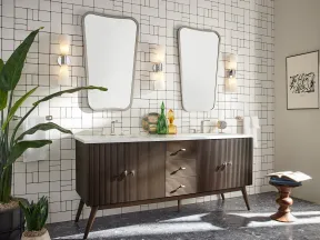 Modern bathroom with mid-century wooden double vanity, two unique mirrors, and geometric white tiled wall.