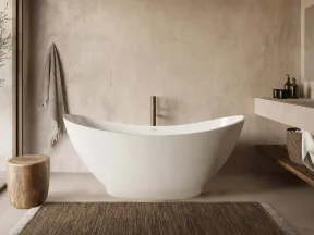 Modern freestanding white bathtub in minimalist bathroom with wooden stool, towel, and neutral-toned decor