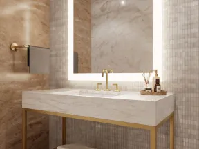 Modern bathroom vanity with marble countertop, gold fixtures, illuminated square mirror, and neatly stacked towels.