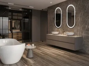 Modern bathroom with freestanding tub, dual vessel sinks, illuminated oval mirrors, and walk-in closet with glass doors.