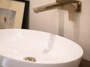 Modern white oval bathroom sink with a wall-mounted brushed metal faucet and single lever handle.