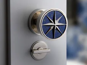 Close-up of a stylish door knob featuring a blue compass star design with a silver lock below on a gray door.