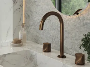 Modern bathroom sink with bronze faucet, marble countertop, round mirror, and natural light from window.