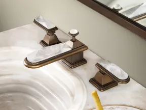 Luxury bathroom sink with gold and marble faucet and a jar of caviar with fries on a decorative plate.