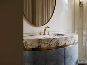 Elegant bathroom vanity with marble countertop, gold faucet, round mirror, and textured blue cabinet.
