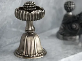 Antique silver doorstop with ornate floral design on marble surface with blurred background.