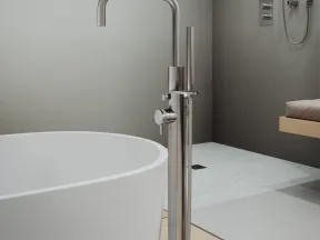Modern bathroom with a freestanding white bathtub and sleek stainless steel floor-mounted faucet and showerhead.