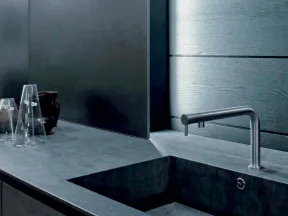 Modern gray kitchen sink with sleek stainless steel faucet and minimalist countertop with glassware and black vase.