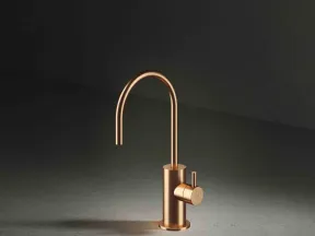 Sleek modern copper kitchen faucet with curved spout and single lever handle on dark surface.