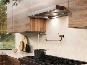 Modern kitchen with wooden cabinets, gas stove, brass pot filler faucet, and a pot boiling water.