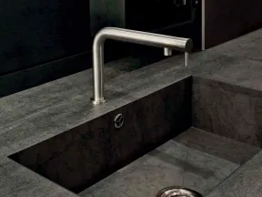 Modern minimalist kitchen sink with dark stone countertop and sleek stainless steel faucet.