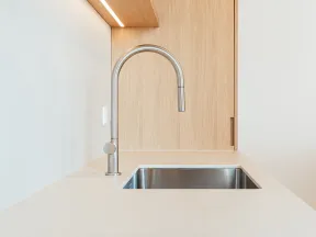 Modern kitchen sink with stainless steel faucet and wooden wall paneling under soft lighting