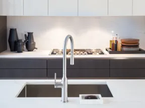 Modern kitchen sink with sleek stainless steel faucet, white marble countertop, and dark cabinetry behind.