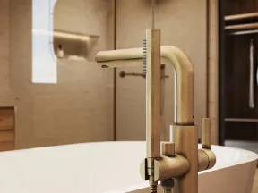Modern brushed brass freestanding bathtub faucet with handheld shower in a stylish bathroom.