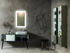 Modern bathroom with glowing rectangular mirror, white sink, minimalist storage, and geometric wall decor on gray walls.