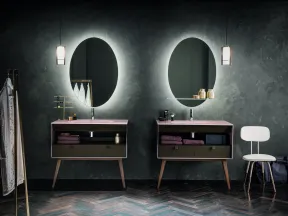 Modern bathroom with two illuminated oval mirrors, wooden vanities, hanging pendant lights, and minimalist decor.