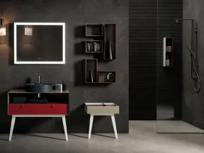 Modern bathroom with illuminated rectangular mirror, black sink on red drawer vanity, and minimalist decor.