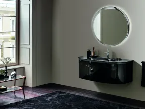 Modern bathroom with a floating black vanity, round backlit mirror, wooden floor, and a window with white shutters.