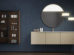Modern bathroom with dark blue walls, floating vanity with textured drawers, round mirror, and glass cabinet.