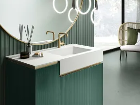 Modern bathroom with green paneled vanity, white countertop, round mirror, brass faucet, and circular pendant lights.