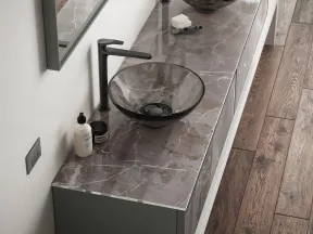 Modern bathroom vanity with double black glass vessel sinks, marble countertop, and wood flooring.