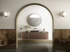 Minimalist bathroom with floating wooden vanity, round mirror, archway, and soft wall sconces lighting.