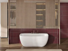 Modern bathroom with a freestanding white tub, burgundy tiled wall, wooden slats, and natural light from large windows