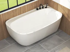 Modern white freestanding bathtub with black fixtures in a wood-paneled bathroom with large window and stone tile floor