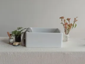 Modern white rectangular sink on a textured tablecloth with plants and dried flowers on both sides