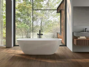 Modern bathroom with freestanding white tub, large floor-to-ceiling window overlooking leafy green trees, wooden floor