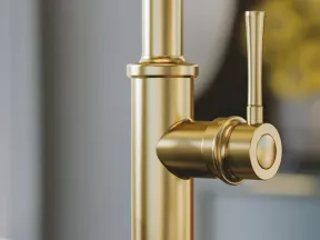 Close-up of a modern gold faucet mounted on a black marble countertop in a stylish kitchen.
