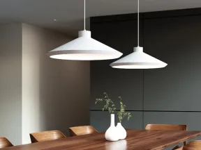 Modern dining room with wooden table, chairs, white pendant lamps, and decorative white vases with greenery.