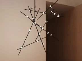 Modern black geometric chandelier with round lights hanging above a wooden table in a minimalist room.