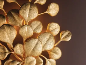 Close-up of a decorative golden metal sculpture resembling stylized leaves or seed pods with textured surfaces.