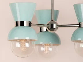 Modern chandelier with three pastel blue shades and exposed filament bulbs against a beige background