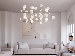 Modern minimalist living room with neutral sofas, abstract art, large chandelier, and man reading by arched windows.